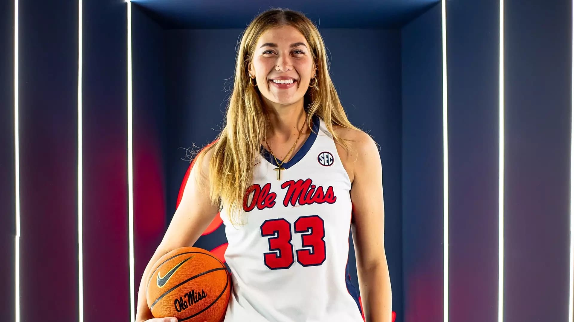 Emily Howard holding a basketball in her white Ole Miss uniform.