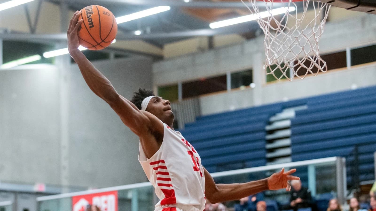 Axis mentor Jahmal Wright reaching for a layup in his white SFU uniform.