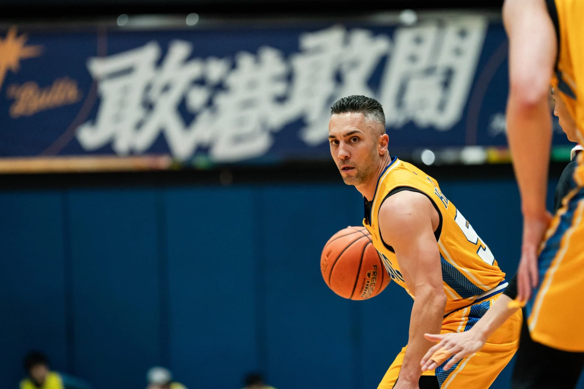 Tyler Kepkay controls the basketball in a yellow Winling uniform during a game.